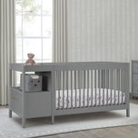 Gray crib with storage drawers in a nursery setting