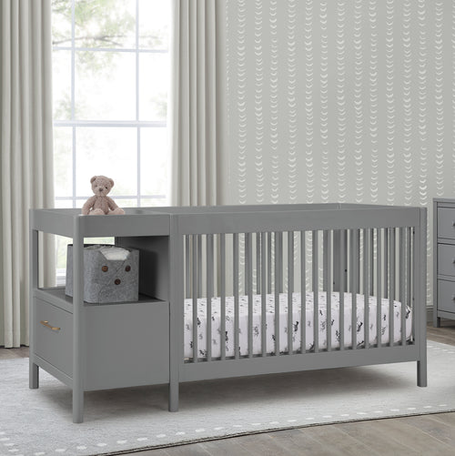 Gray crib with storage drawers in a nursery setting