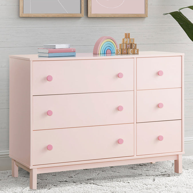 Pink dresser with colorful decor items against a light gray wall. 10-babyGap Legacy 6 Drawer Dresser with Interlocking Drawers