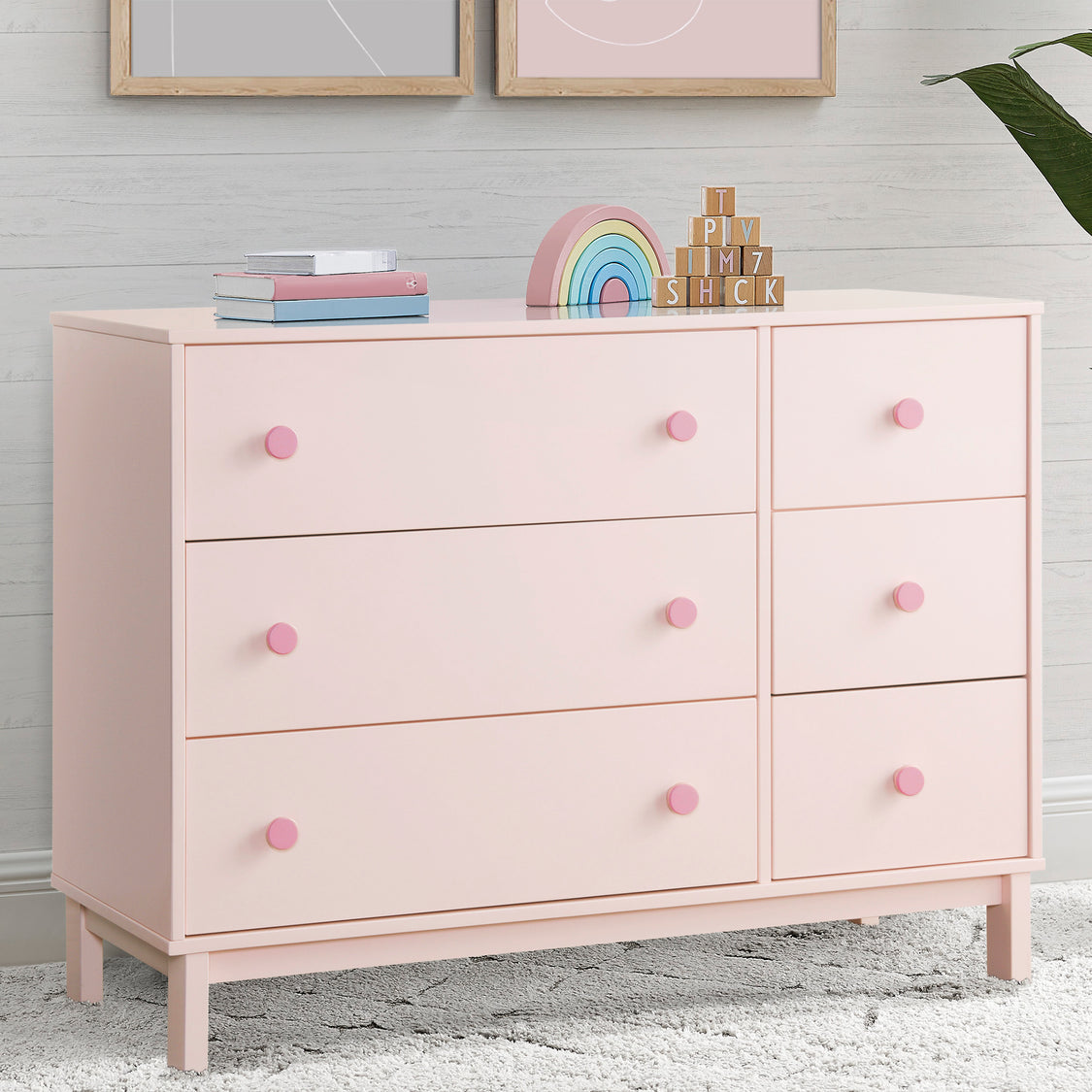 Pink dresser with drawers and pink knobs in a room setting.