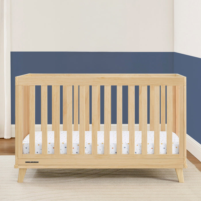 Wooden crib with a white mattress against a blue wall 3-Frankie 4-in-1 Convertible Crib