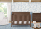 Nursery room with a wooden crib, white rug, and decorative wall paper. 19-Kendall 6-in-1 Convertible Crib