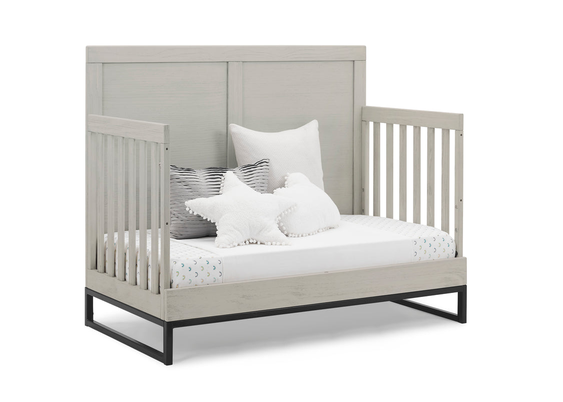 Gray crib with white bedding and pillows on a white background
