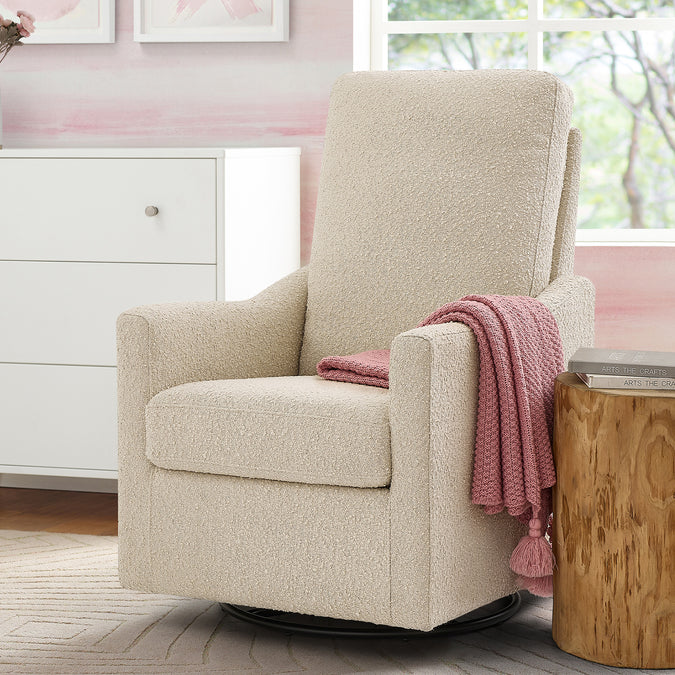 Beige armchair with a pink blanket in a room with a dresser and window. 29-Andie Boucle Nursery Glider Swivel Chair