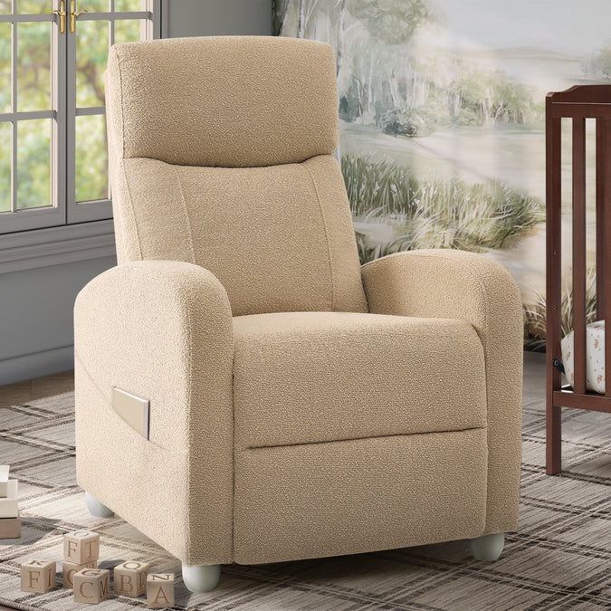 A beige upholstered recliner chair with rounded arms, a high back, and white feet, shown in a styled room setting with a window, rug, wall art, and crib visible. 28-Riley Pushback Stationary Recliner