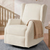 An off-white bouclé wingback recliner chair with a tan throw blanket draped over the arm, set in a styled room with a wooden floor, patterned wallpaper, and a small side table. 17-James Swivel Recliner