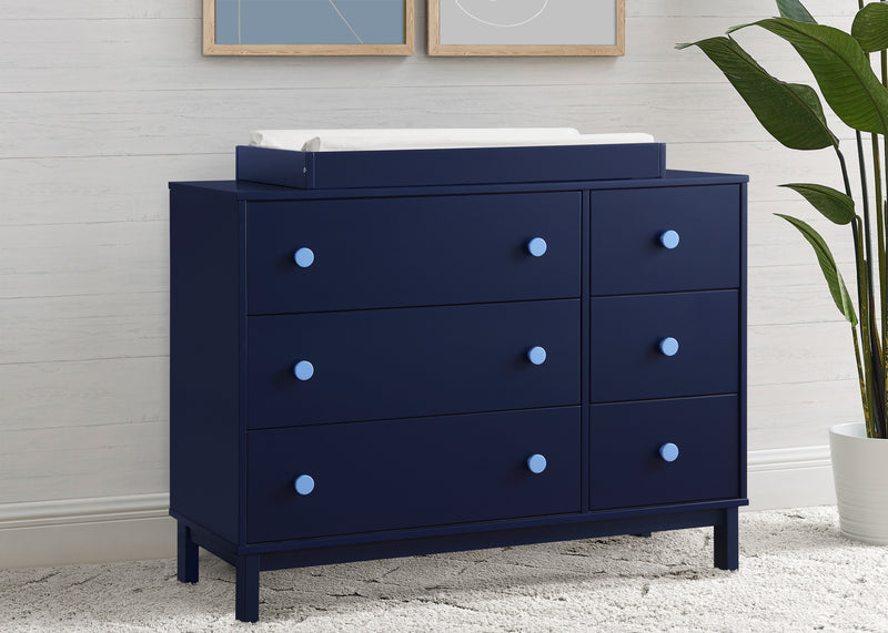 Navy blue dresser with white top in a room with a plant and framed pictures. 23-babyGap Legacy 6 Drawer Dresser with Interlocking Drawers