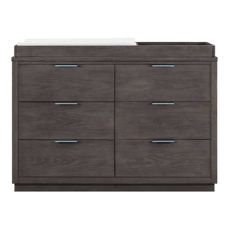 A modern six-drawer dresser in a dark gray wood grain finish with sleek horizontal bar handles, featuring a white countertop with a built-in changing tray on the right side, shown against a plain white background.