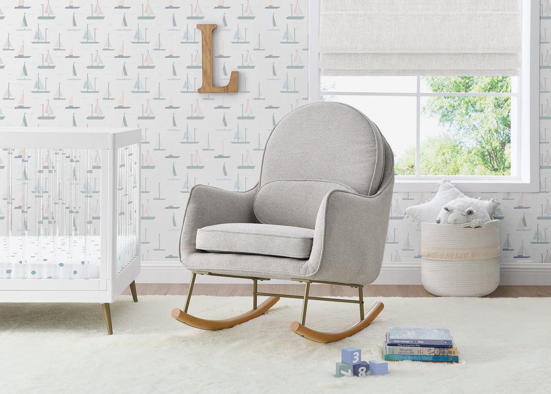 Gray rocking chair in a nursery with white crib and patterned wallpaper.