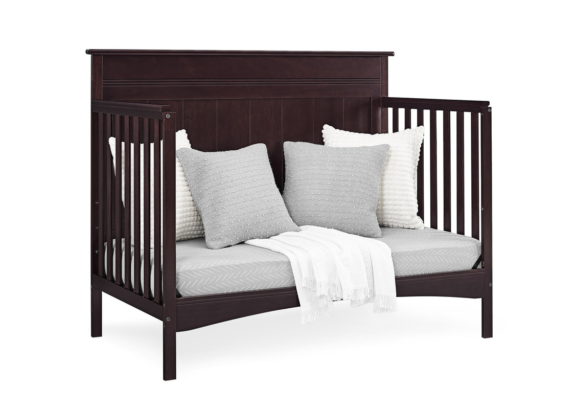 Dark wood crib with white bedding and pillows on a white background