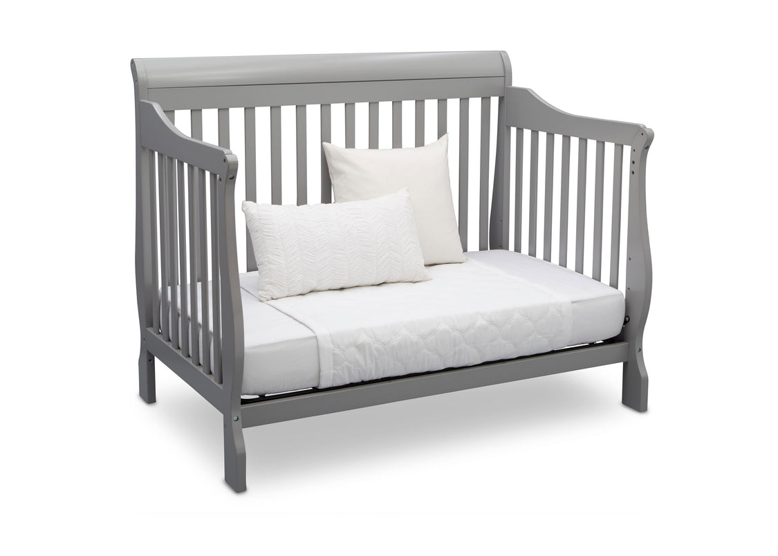 Gray crib with white mattress and pillows on a white background