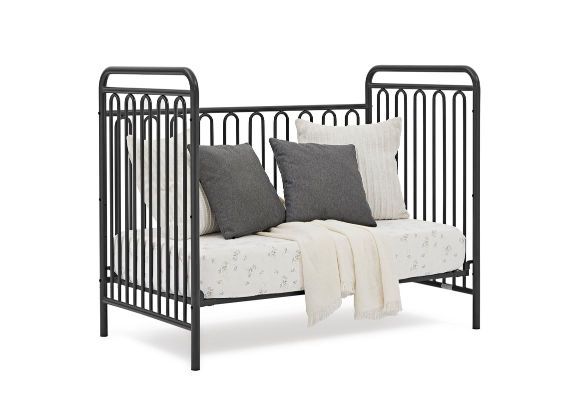 Black metal crib with bedding on a white background