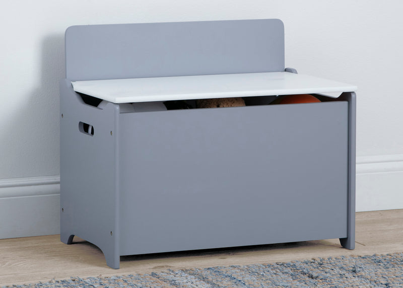 Gray toy storage bench with white top on a wooden floor. 5-GapKids Toy Box