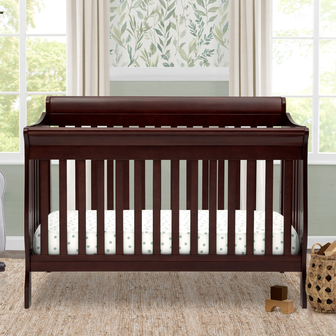 Wooden crib in a nursery with a window and decorative wall in the background