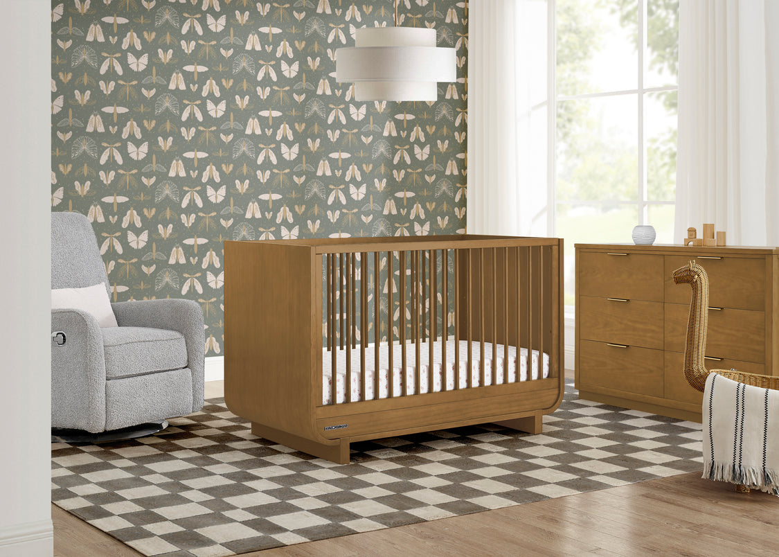 Nursery room with wooden crib, gray armchair, and patterned wallpaper.