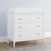 White dresser with gold knobs against a light blue wall. 13-Casey 3 Drawer Dresser with Interlocking Drawers