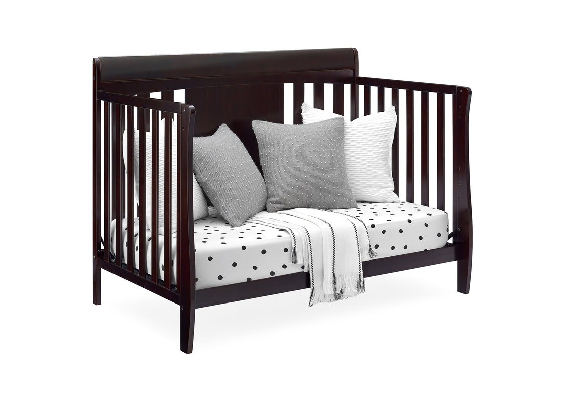 Wooden crib with pillows and a blanket on a white background