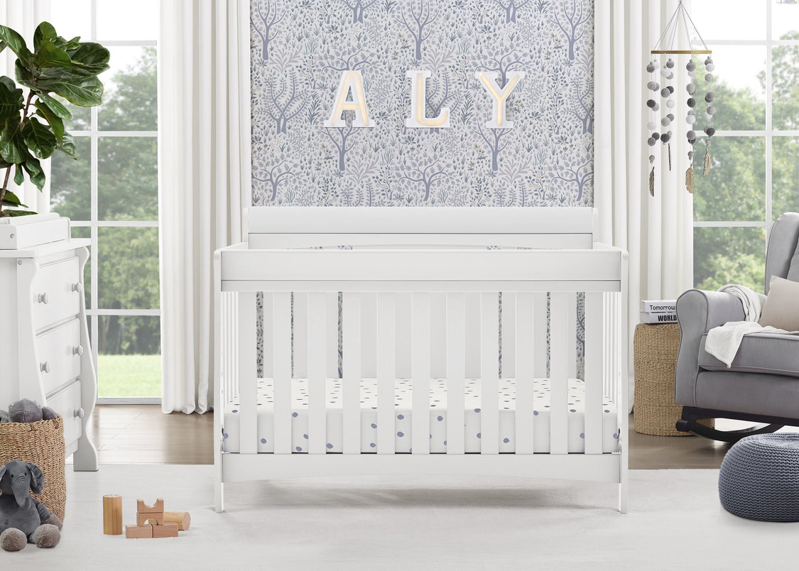 White crib in a bright nursery with decorative elements and a large window.