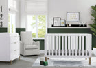 Nursery room with white crib, armchair, and changing table in a bright room. 17-Hendrix 4-in-1 Convertible Crib