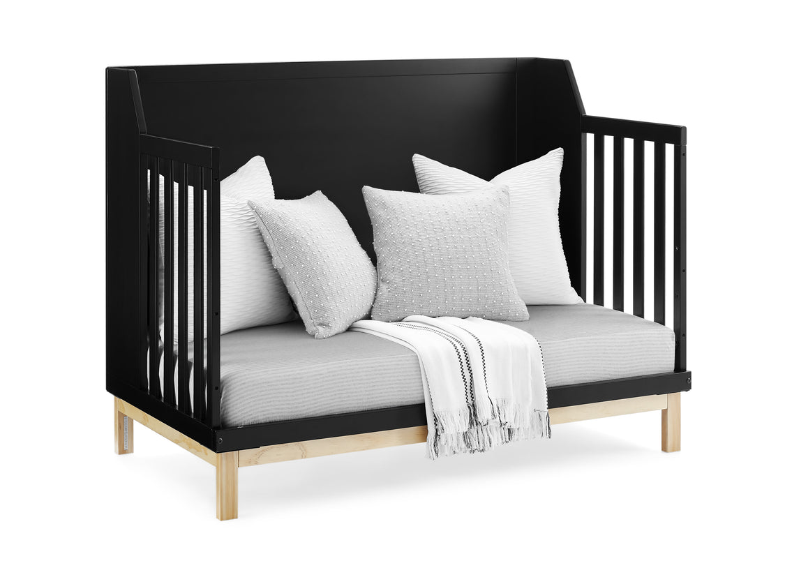 Black crib with white bedding and pillows on a white background