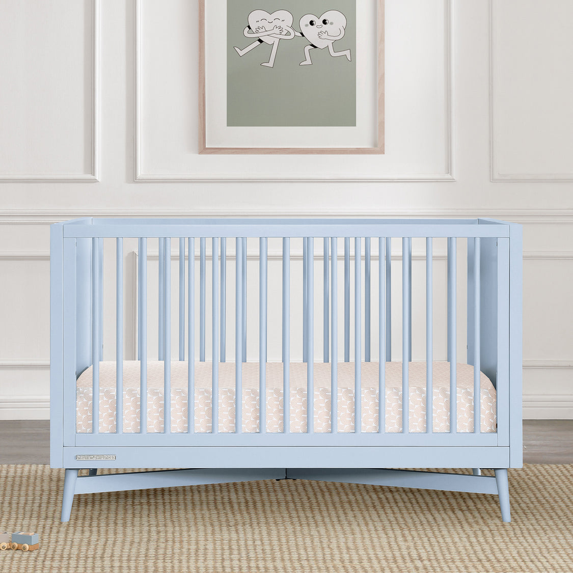 Light blue crib in a room with a framed picture on the wall.