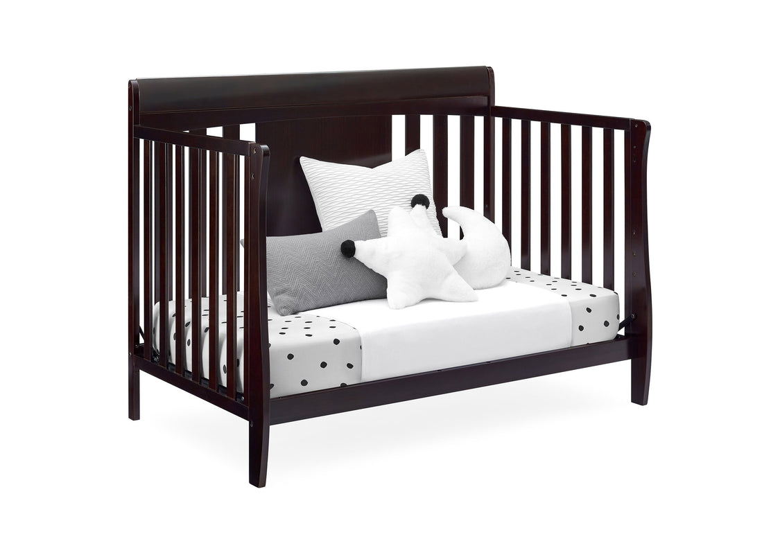 Wooden crib with white bedding and decorative pillows on a white background
