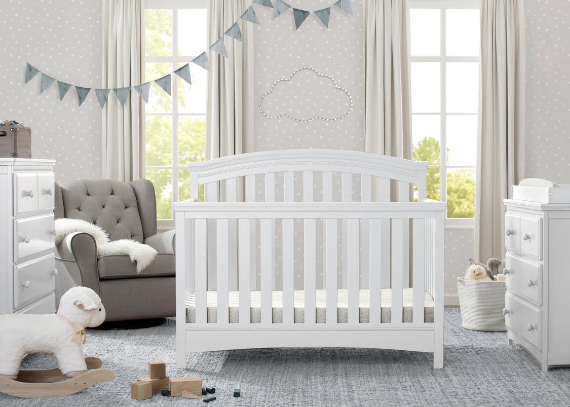 White crib in a nursery with gray walls, white furniture, and decorative elements.