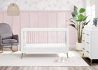 Nursery room with a white crib, gray chair, and pink wall. 23-Sloane 4-in-1 Acrylic Convertible Crib