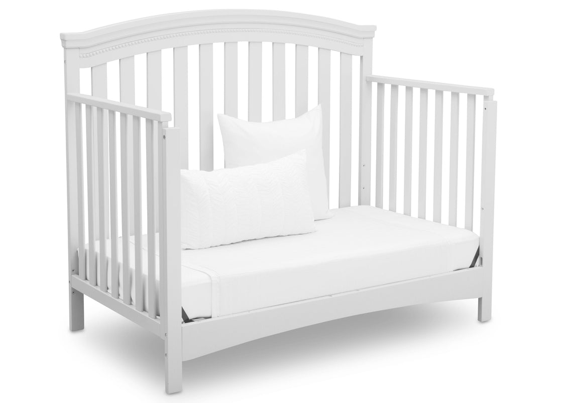 White crib with a mattress and pillow on a white background