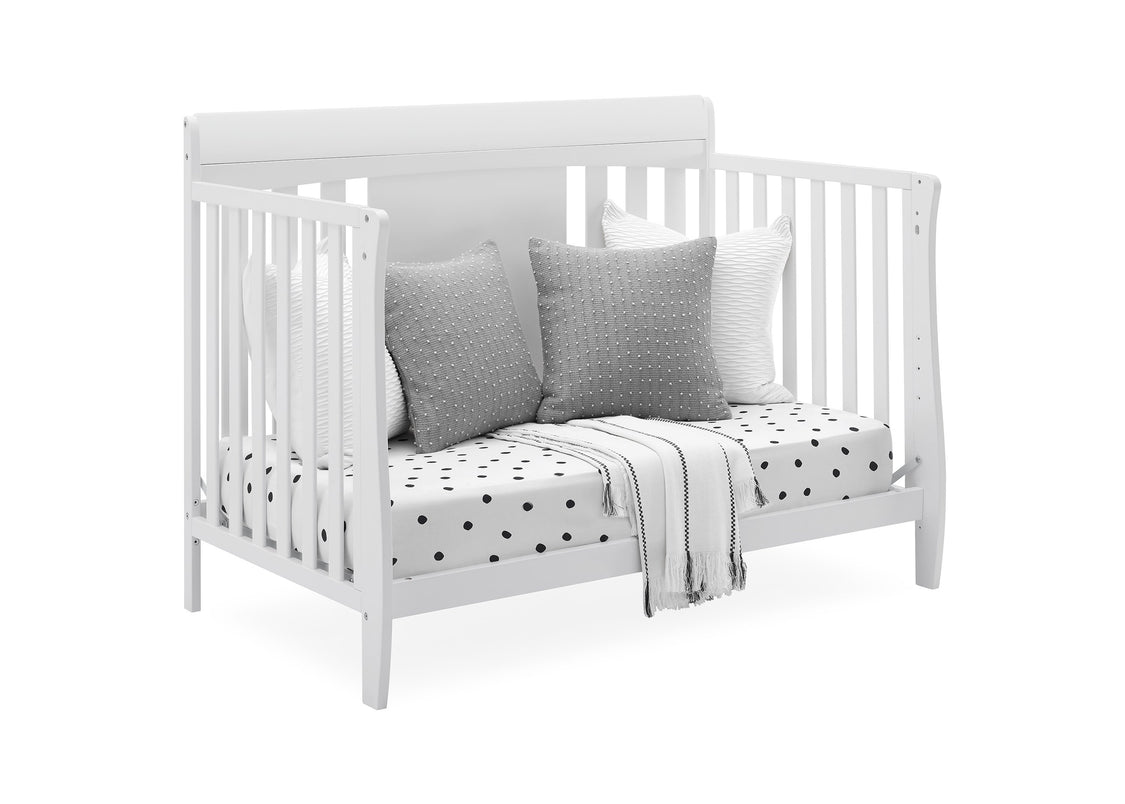 White crib with gray pillows and a polka dot blanket on a white background