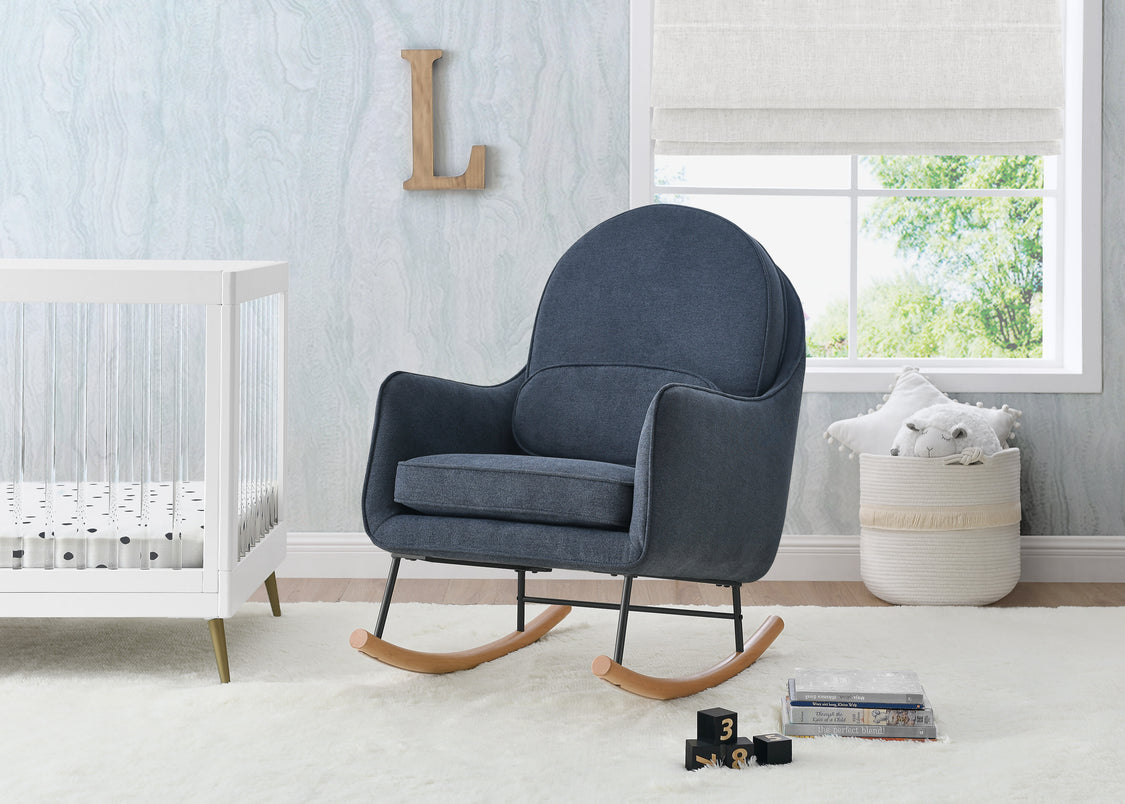 Blue rocking chair in a nursery with a crib and window in the background