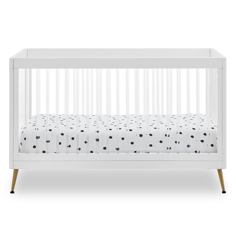 White crib with a polka dot mattress on a white background