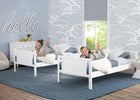 Two children playing on white beds in a room with blue walls and decorative elements. 10-Convertible Twin Bunk Bed with Ladder and Guardrails