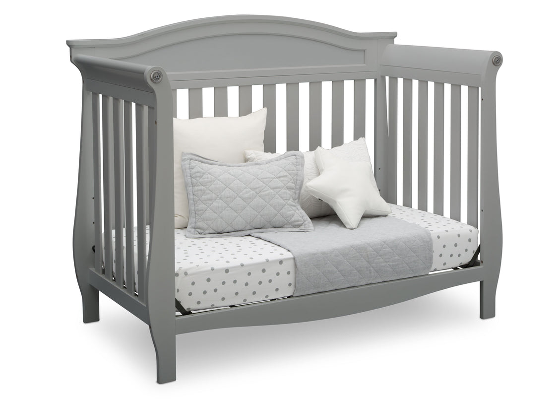 Gray crib with bedding and pillows on a white background