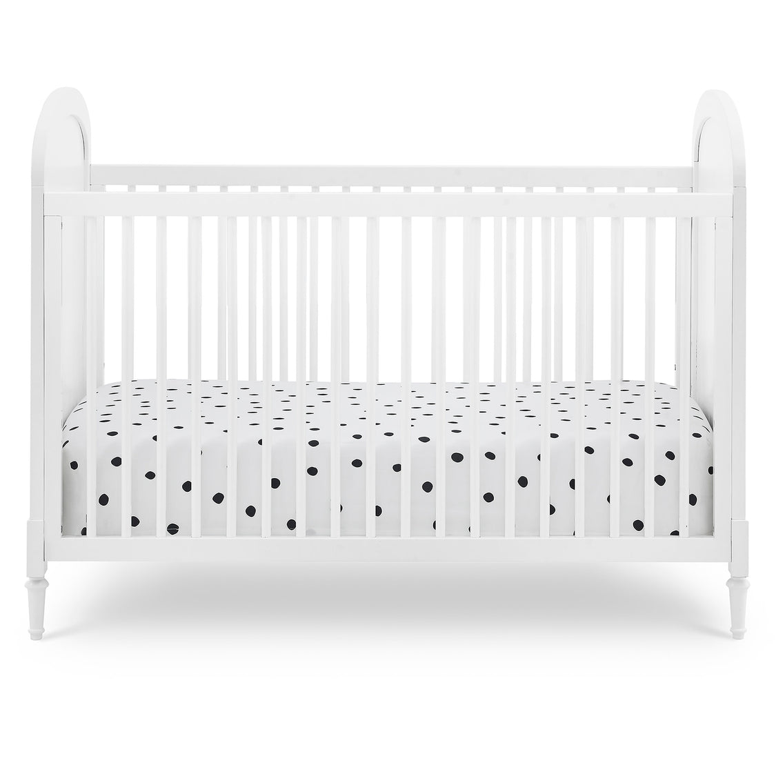 White crib with a black and white polka dot crib sheet on a white background