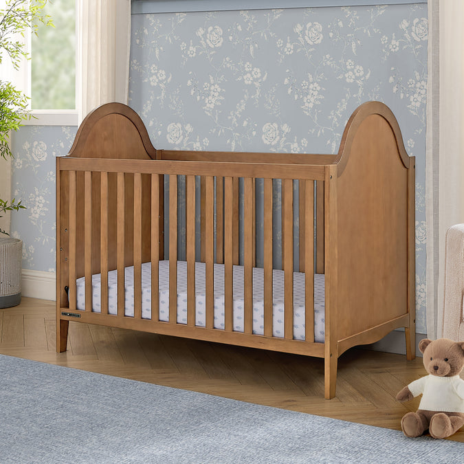 Wooden crib in a nursery with floral wallpaper and a teddy bear. 30-Willa 4-in-1 Convertible Crib