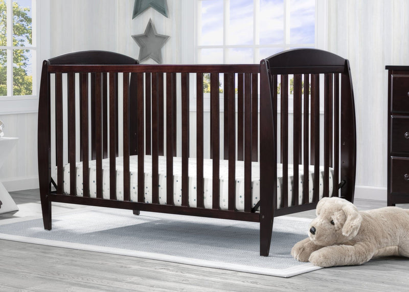 Wooden crib in a nursery with a teddy bear on the floor.