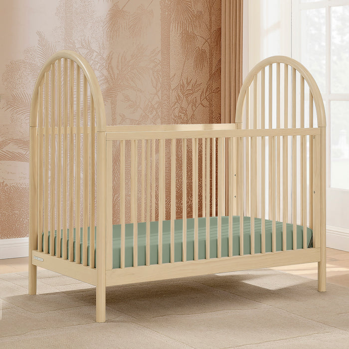 Beige crib with a green mattress in a room with patterned wallpaper and a window. 1-Cannon 4-in-1 Convertible Crib