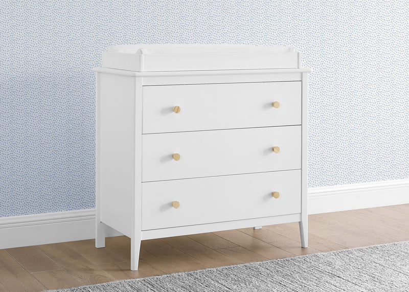 White dresser with gold knobs against a light blue wall with subtle pattern 12-Casey 3 Drawer Dresser with Interlocking Drawers